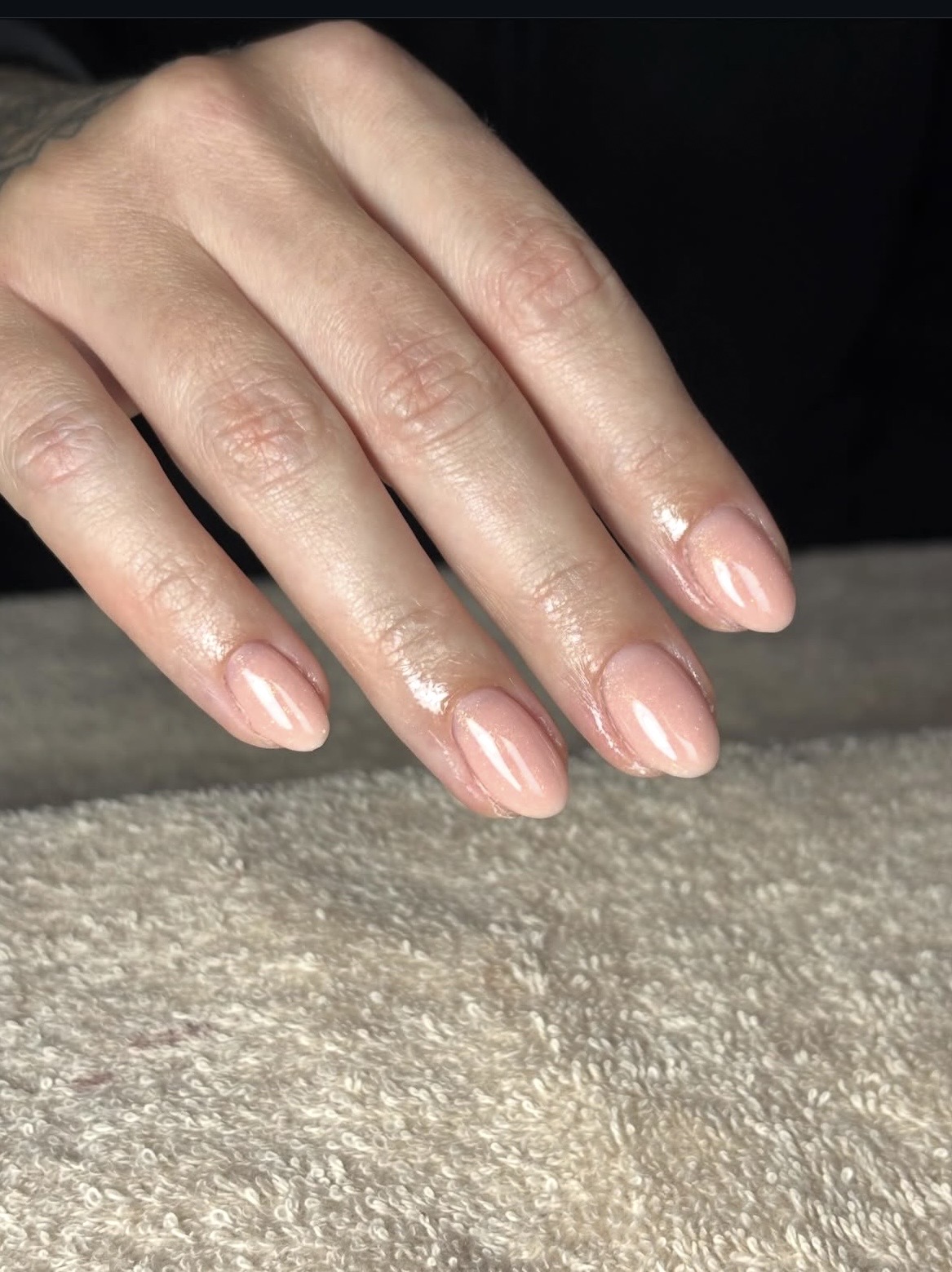 Naturel gelakte BIAB nagels op een crèmekleurige handdoek